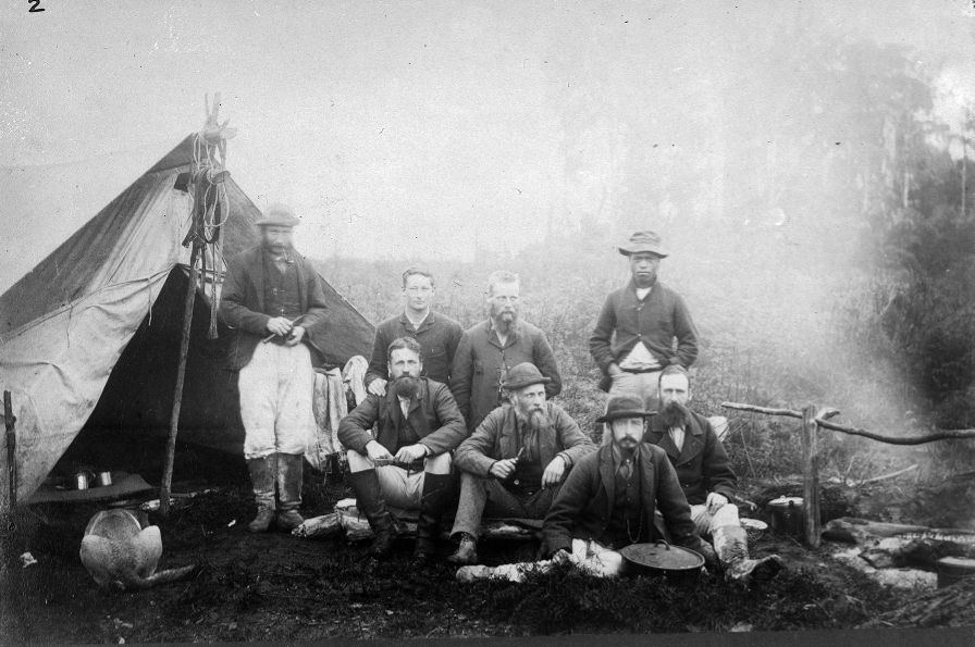 Stephenson Percy Smith and his survey party - Smith is sitting in the front wearing a hat and holding a pipe (1886). Unknown photographer. Collection of Alexander Turnbull Library (1/2-061056-F).